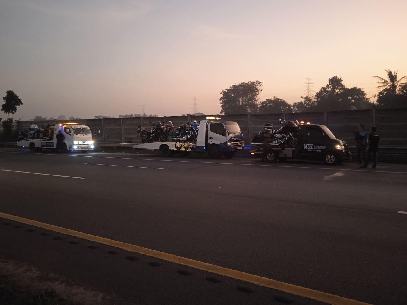 Armada Max Towing membawa motor besar di jalan tol saat senja