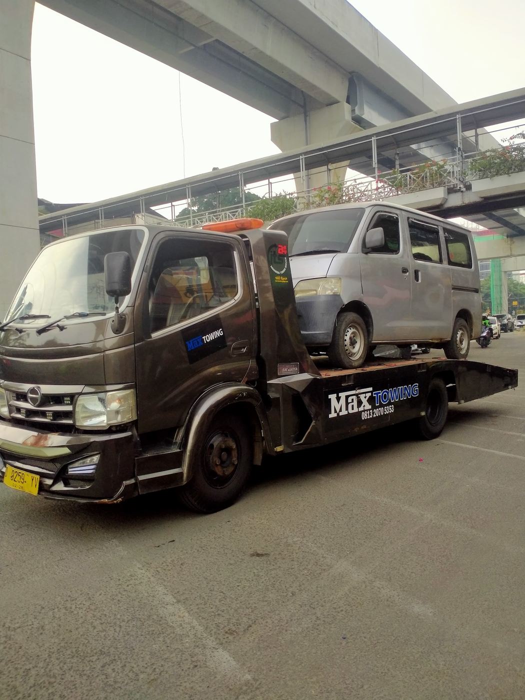 Truk Max Towing mengangkut mobil di bawah jalur layang Jakarta